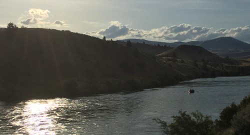 Evening light on the Deschutes and a drift boat gliding downstream.